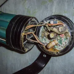 Uszkodzona instalacja elektryczna w domu, objawy: spalone przewody, skorodowane kondensatory i cewka.